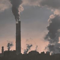 Image of smokestacks with plumes of smoke coming out of them