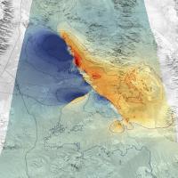 This is a primarily grayscale, topographic image showing the ridges, peaks, valleys, and flatlands of the area.In the center of the image is a swath of area highlighted in green. Within that zone are areas on the left side colored blue, and areas colored orange and red on the right.