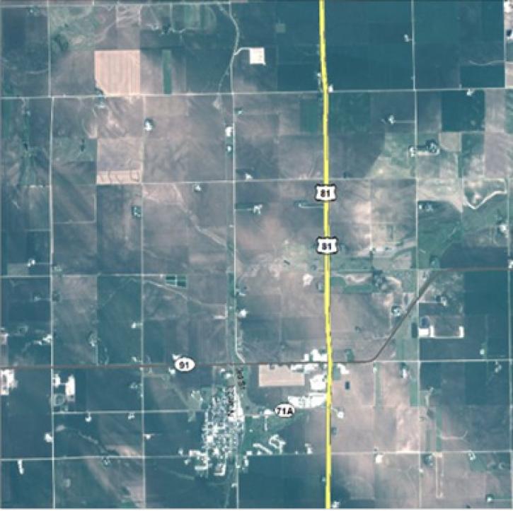 Image of green agricultural fields laid out in squares with a yellow highway down the ceter