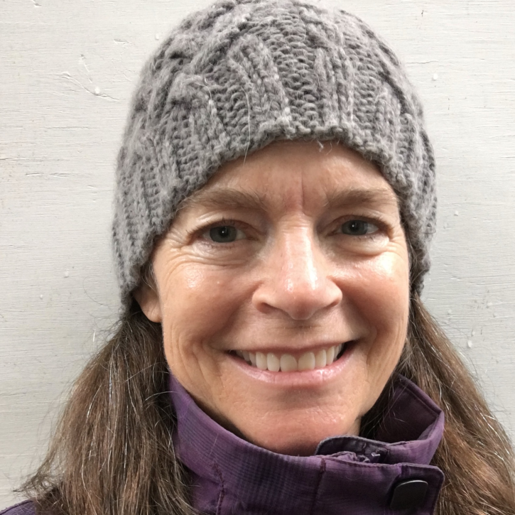 Headshot of Anne Nolin wearing a beanie and standing in front of a wall