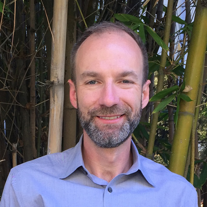 Headshot of Brian standing outside in front of bamboo