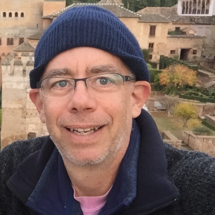 Headshot of brian mapes standing outside in front of a town