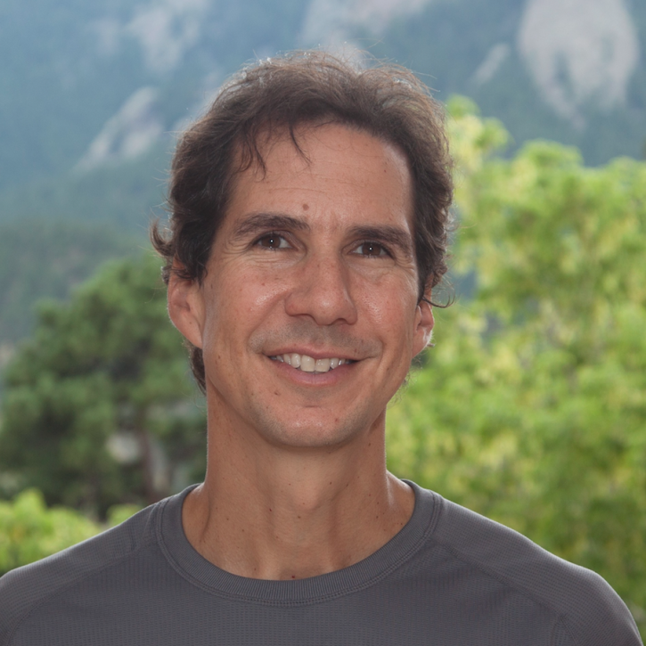 Headshot of john fasullo stanging out side with mountains in the background