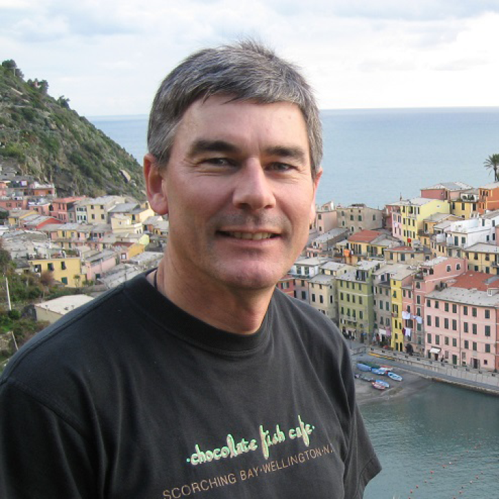 Headshot of wilkin standing on a hilltop with a town behind him