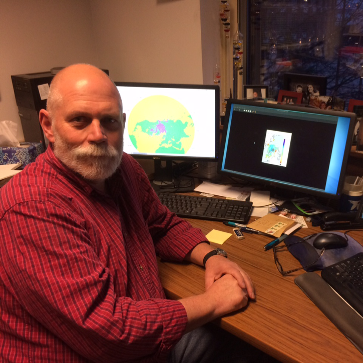 headshot of anderson sitting at his desk wearing a red check shirt