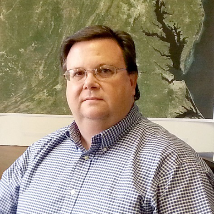 headshot of trice sitting in front of a topo map of Maryland