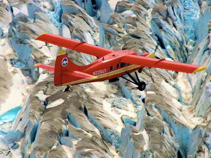 A red airplane is in flight against a blue-and-tan patterned background.