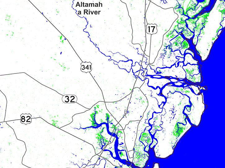 The rectangular image is a map of the St. Simons Island area of coastal Georgia. Land is colored white, roadways are black, inundated vegetation area are green, and water is colored blue. The Atlantic Ocean is in the lower-right of the image and its blue shaded area extends into waterways along the coast.