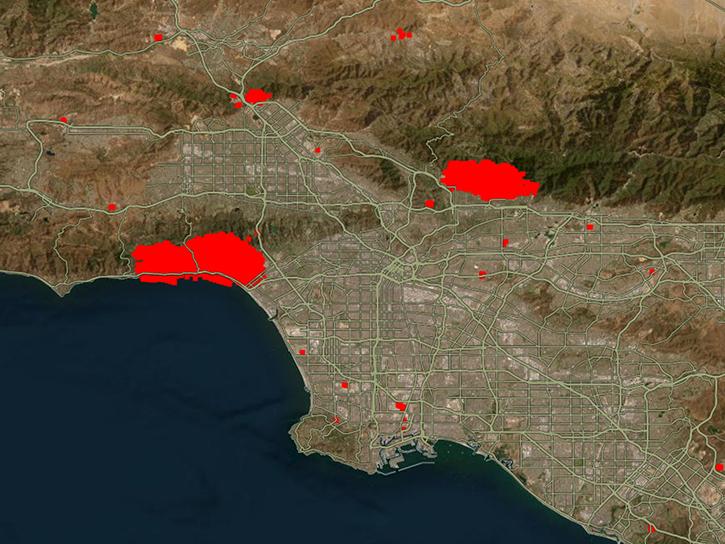 A satellite image of the West Coast shows the ocean in dark blue, land in shades of brown, and wildfire hotspots in bright red.