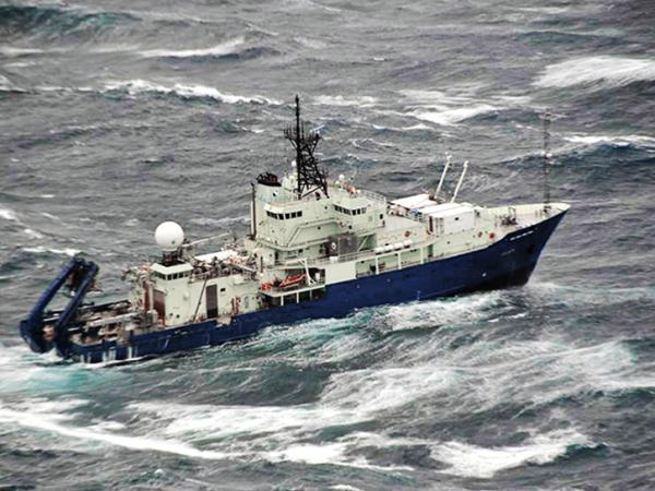 A ship navigates choppy gray waters with visible whitecaps.