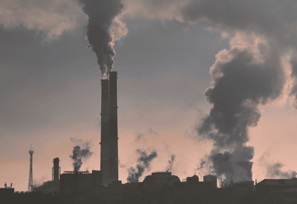 Image of smokestacks with plumes of smoke coming out of them