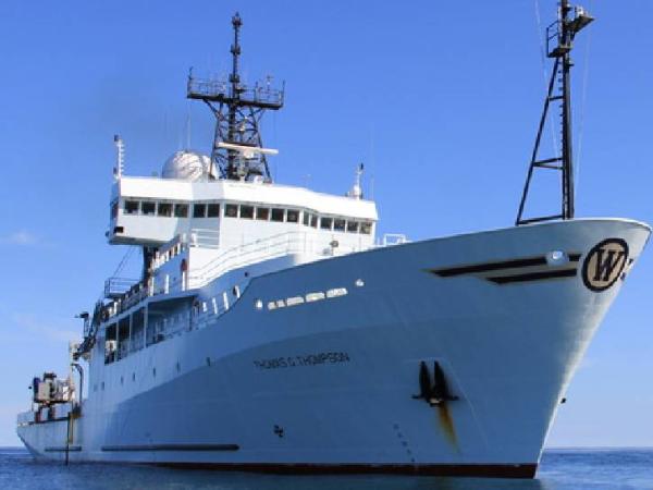 Image of the RV Thompson from the NASA PISTON campaign. it's a large white ship on the sea with several instruments visible on the top of the vessel
