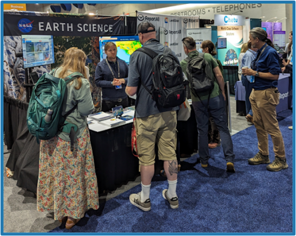 Image of NASA booth at Esri with numerous people standing in front and one NASA representative inside the booth interacting with visitors