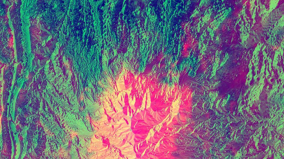 This overhead view shows a mountainous area. Most of the image and terrain is colored in shades of green. In the center is the peak of a mountain colored in yellow and pink.