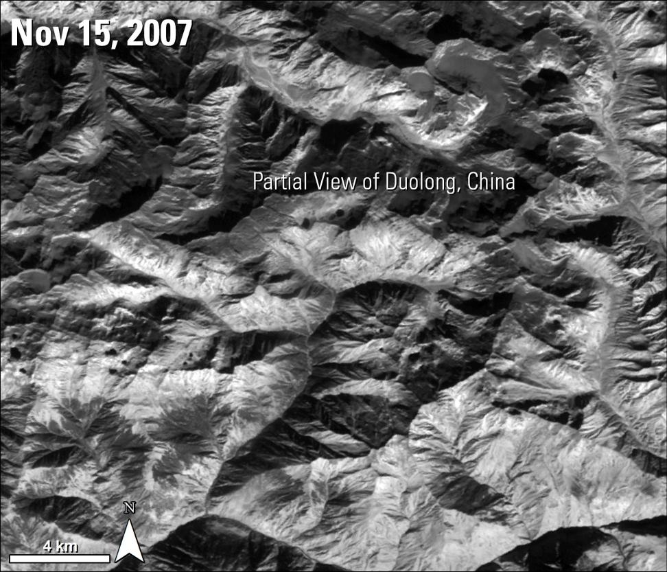 This is a black and white image of the terrain in Duolong, China. Visible are the peaks, valleys, and rideglines that make up the area. Text in the middle of the image reads Partial View of Duolong, China. In the upper left-hand corner is the text Nov 15. 2007.