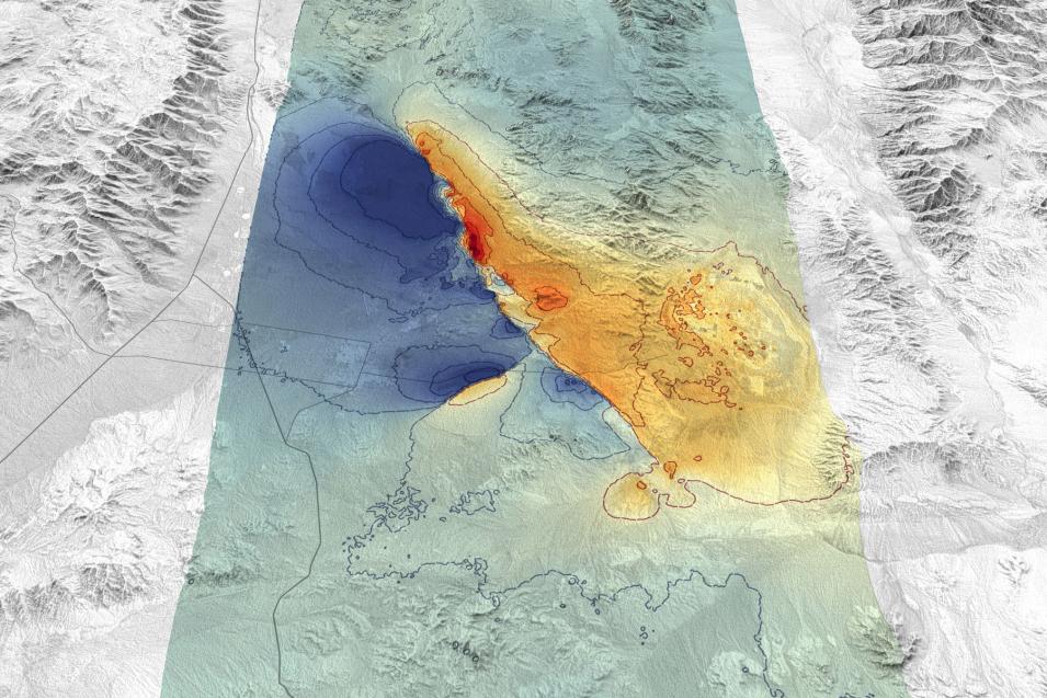 This is a primarily grayscale, topographic image showing the ridges, peaks, valleys, and flatlands of the area.In the center of the image is a swath of area highlighted in green. Within that zone are areas on the left side colored blue, and areas colored orange and red on the right.
