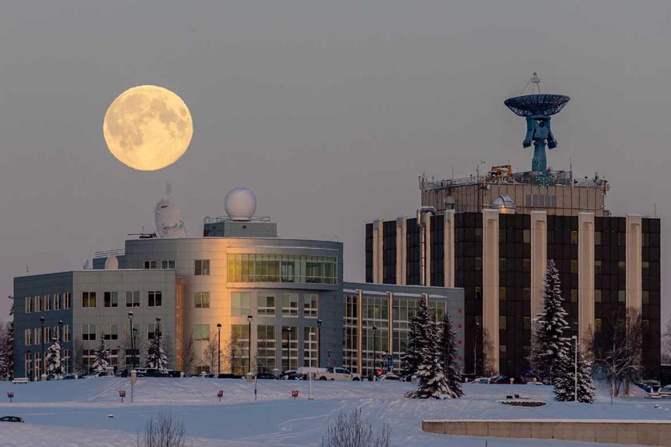 View of the Elvey building with NASA antenna with the rising full moon behind it.
