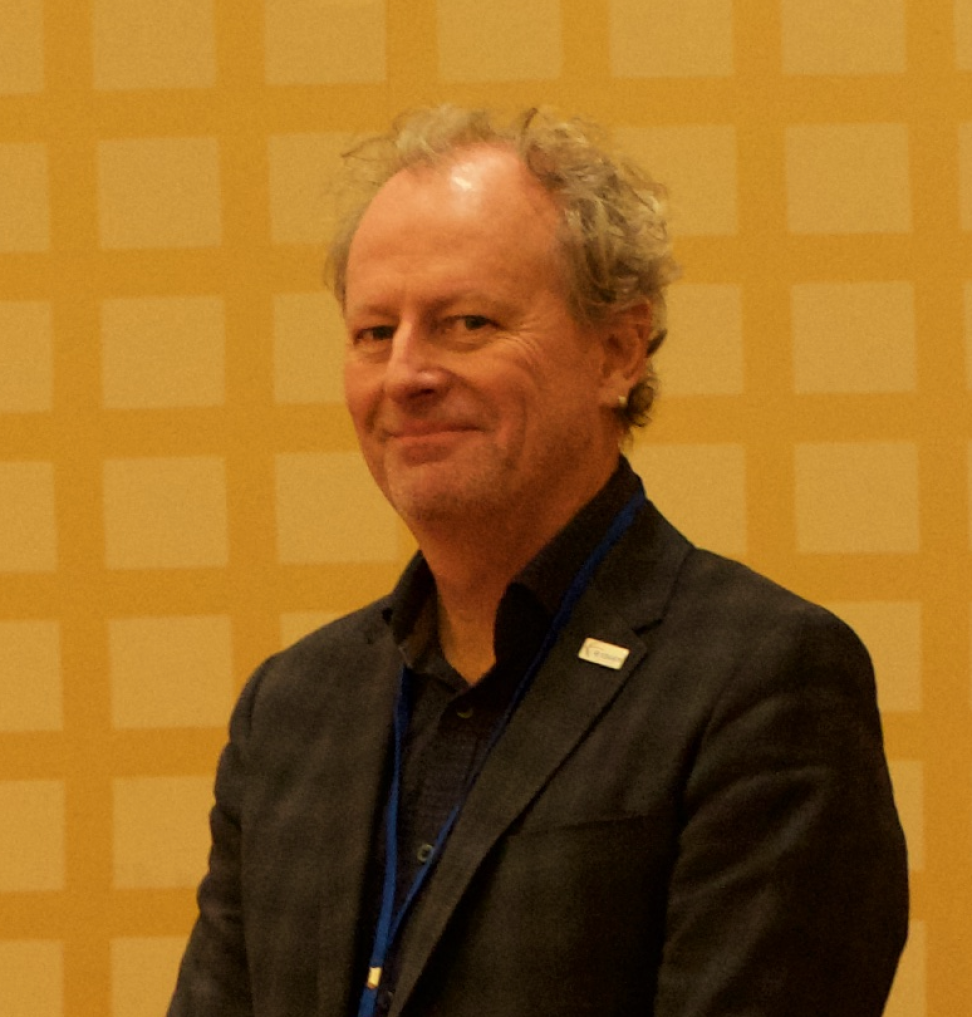 Headshot of Dr. Peter Fox taken indoors against a yellow wall.