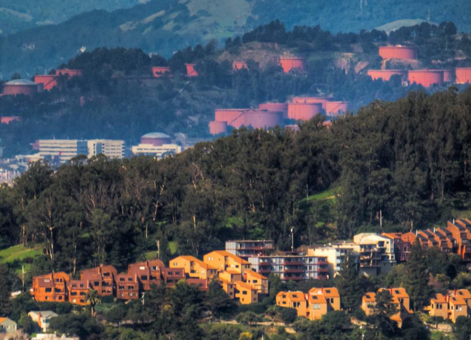 Photograph of giant oil tanks interspersed with residentail houses