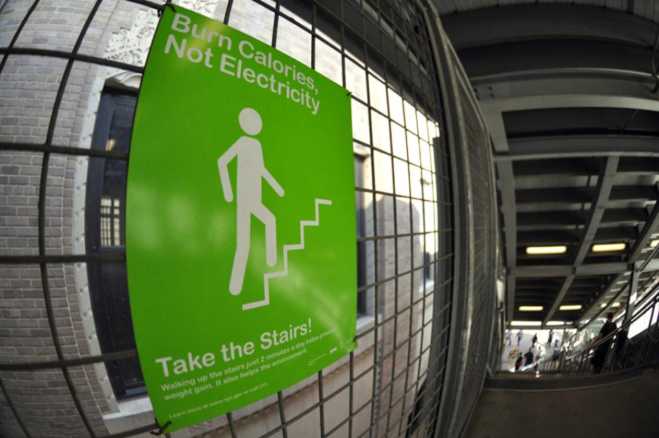 Photograph of a sign from a New York subway encourages people to burn calories rather than electricity