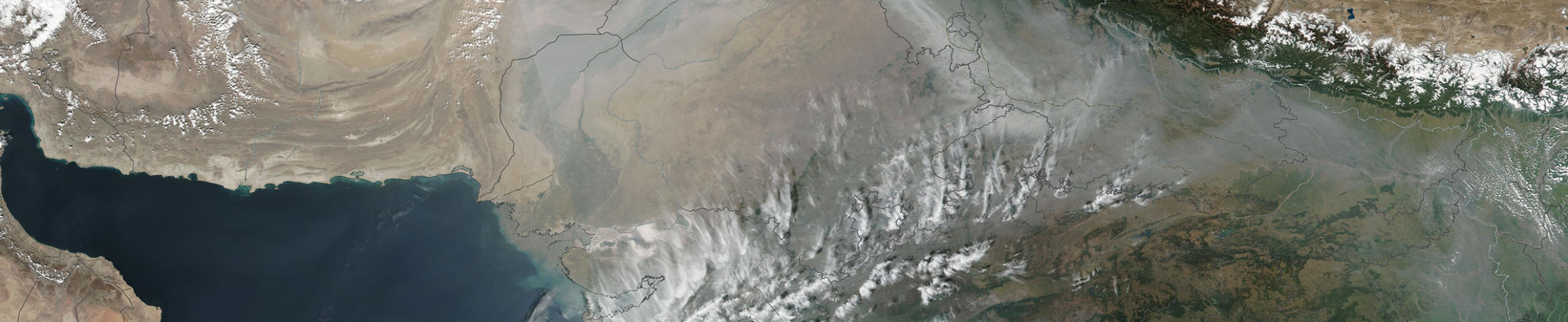 The image is a satellite view of thick haze and air pollution along the southern edge of the Himalayan Mountains in Northern India and Nepal. 