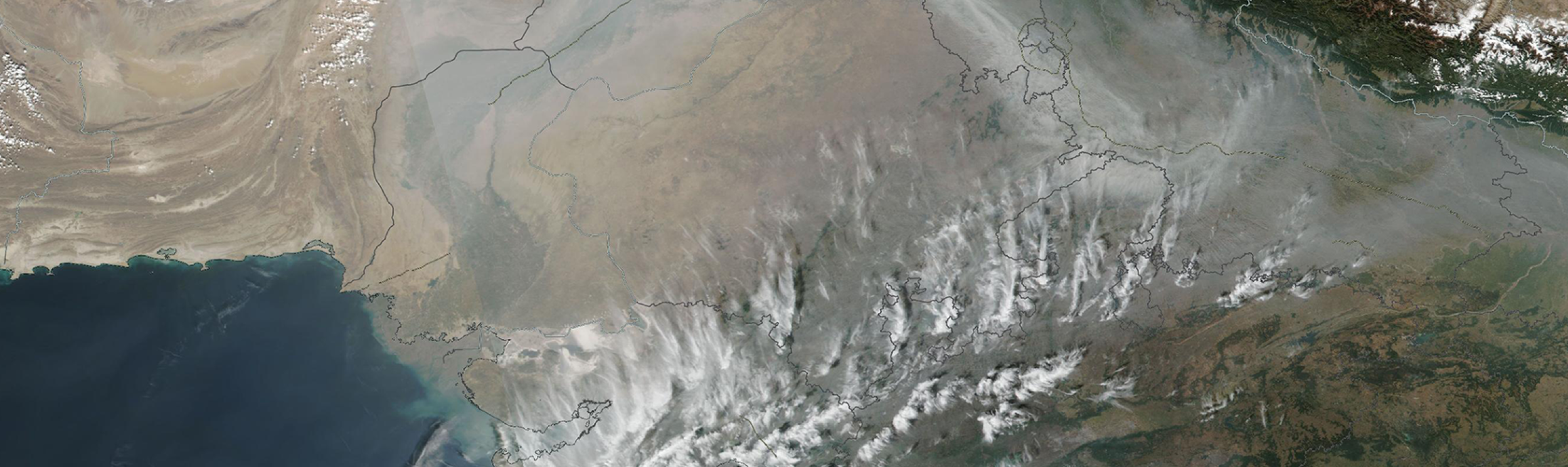 The image is a satellite view of thick haze and air pollution along the southern edge of the Himalayan Mountains in Northern India and Nepal. 