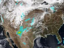 Satellite imagery of Earth shows much of the United States beneath wispy white clouds, with areas of concentrated dust colored teal and yellow.