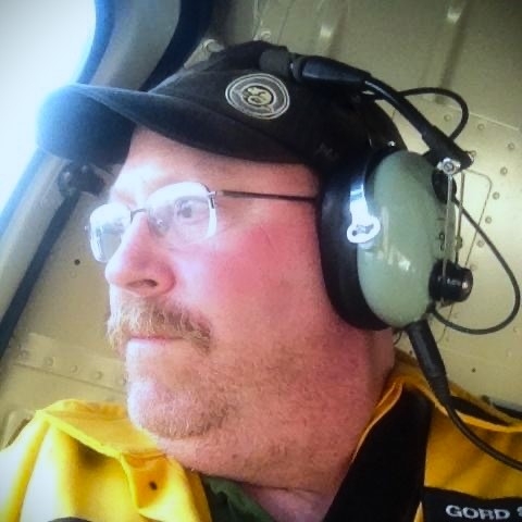 Gordon Seymour, GIS and Wildfire Data Technician with the Department of Environment and Climate Change for the government of Canada's Northwest Territories looks for fires from a helicopter.